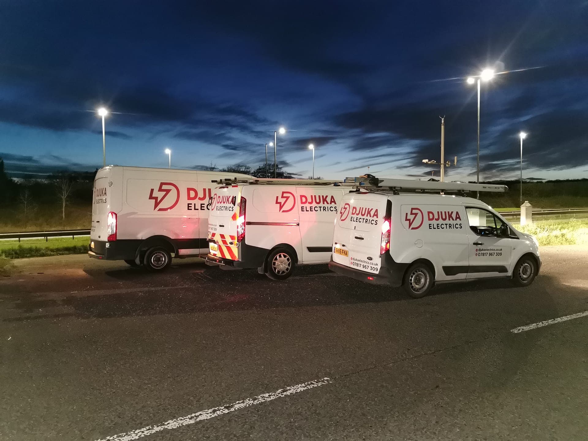Three Djuka Electrics vans parked at twilight under street lights, the team rolling out for an early start