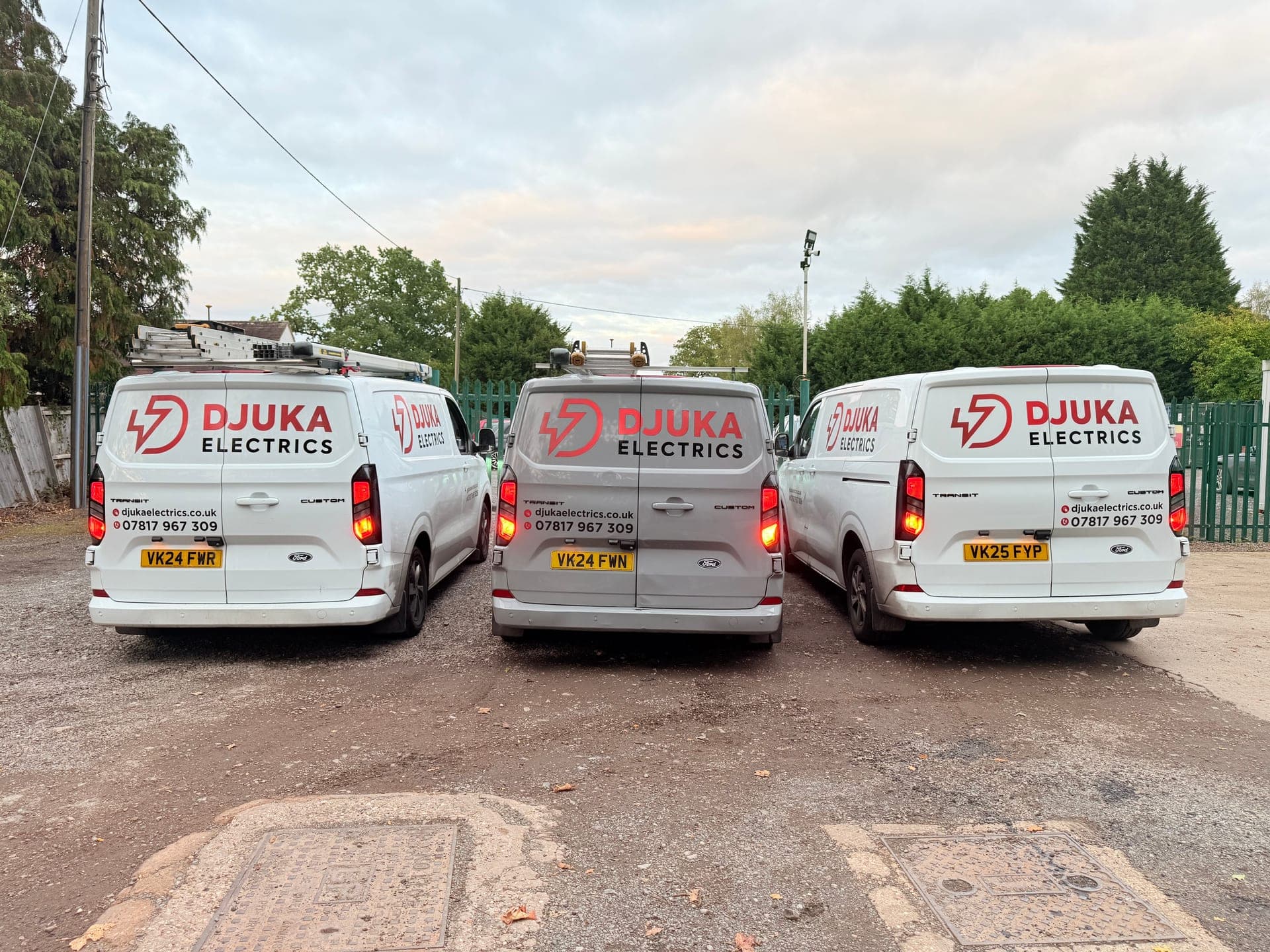 Three Djuka Electrics branded vans lined up rear-on in the yard, ready for the day