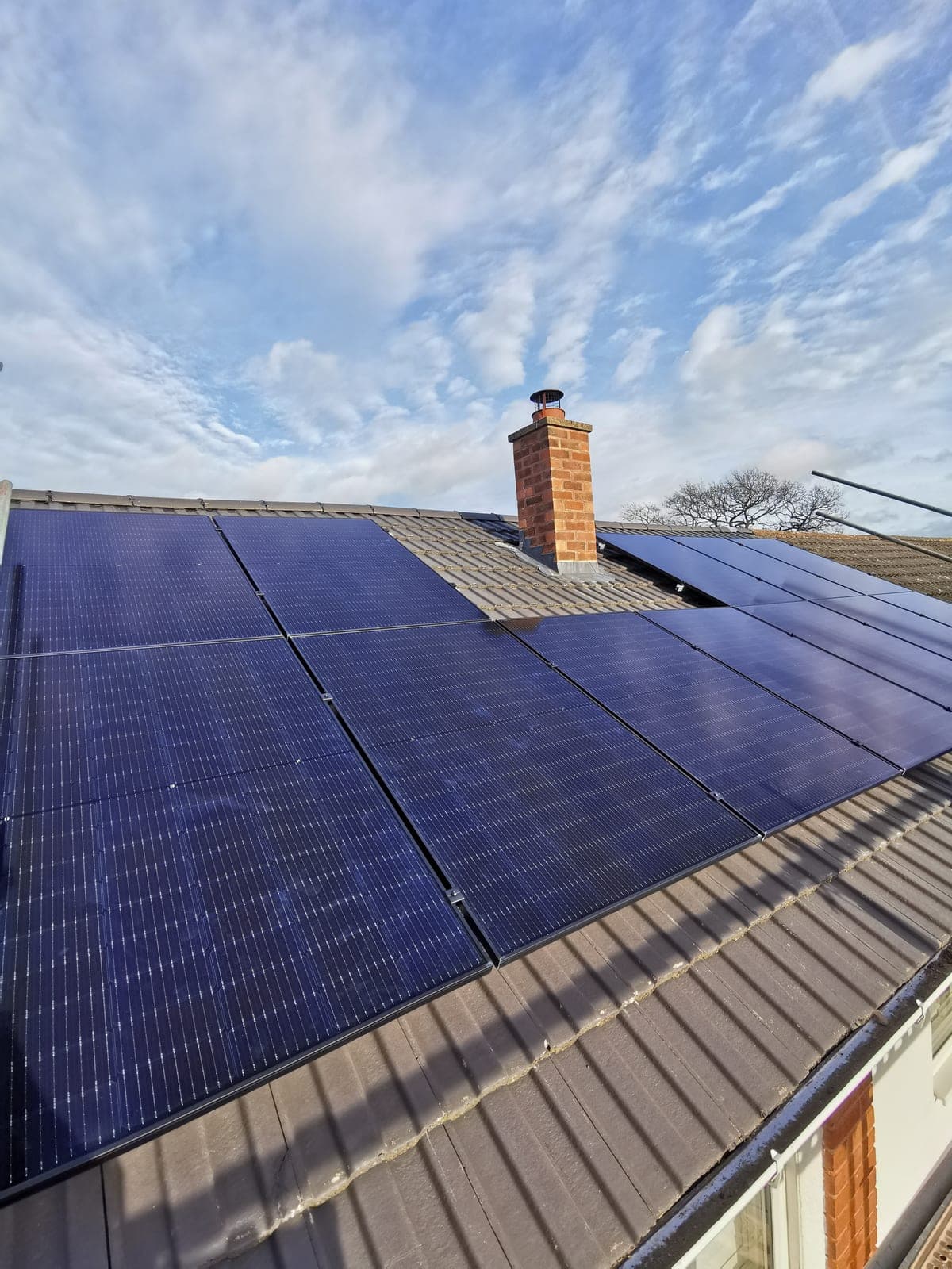 Black solar panels installed around a brick chimney