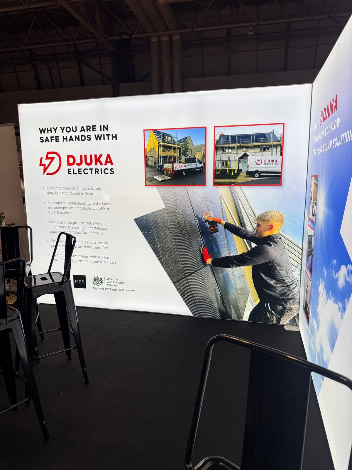 Djuka Electrics trade show stand showing the 'Why You Are In Safe Hands' presentation banner with MCS and OZEV credentials